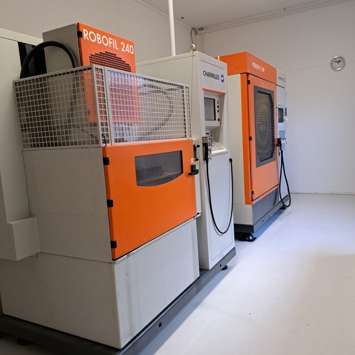 Charmilles Drahterodiermaschinen Zwei Maschinen mit orangefarbenen und grauen Gehäusen in einem hellen Raum.